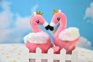 Detail of pink plush flamingo keychain with golden crown and colorful fluffy wings