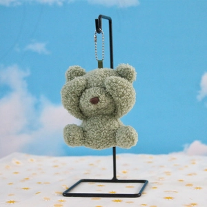 Close-up of green curly plush bear pendant with see-no-evil pose and silver chain