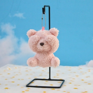 Close-up of pink plush bear pendant with curly lamb wool texture and silver metal chain