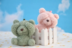 Detail of plush shy teddy bear pendants in green and pink with metal bead chains