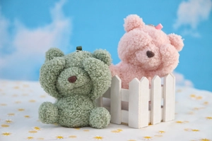 Detail of pink and green plush shy bear pendants with soft teddy fleece texture
