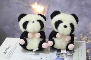 Nahaufnahme von Panda-Plüschanhängern mit rosa Pfotendetails auf einem Zeitschriftenhintergrund