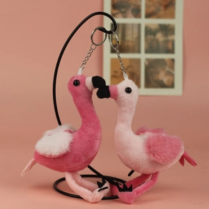 Detail of pink flamingo plush keychains hanging on a stand with a warm background