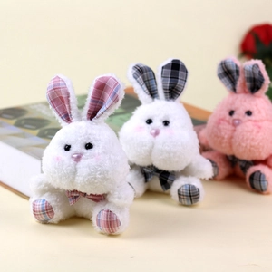 Detail of plush bunny keychain in white and pink with stylish plaid bow and soft fur