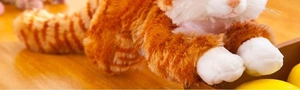 Dettaglio di gatto di peluche a strisce arancioni con zampe bianche su legno caldo