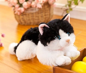 Gatto di peluche realistico bianco e nero con occhi blu su sfondo in legno accogliente