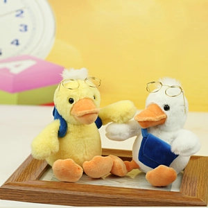 Detail of plush duck set with metal glasses and blue backpack in warm wooden frame