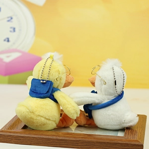 Detail of yellow and white plush duck keychains with glasses and metal bead chains