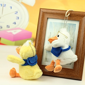 Detail of plush duck keychains with metal glasses and blue bags in yellow and white colors