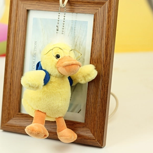 Detail of yellow plush duck keychain with round glasses and a blue backpack accessory