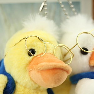 Close-up of plush duck keychains with round glasses and blue scarves for bags