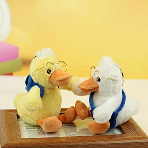 Detail of cute plush duck charms with gold glasses and blue backpacks for bags