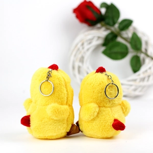 Detail of plush yellow chicken keychains with soft faux fur and metallic ring on white decor