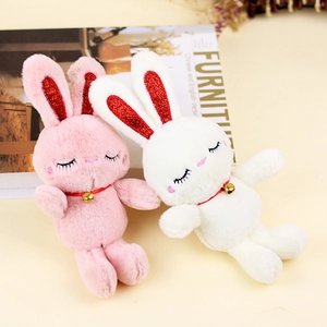 Detailed view of plush bunny keychains with long ears, gold bells and sleep embroidery