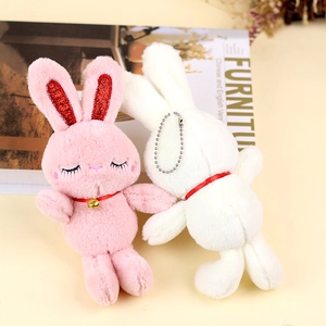 Close-up of plush bunny charms with sequin ears and gold bells on a cozy background
