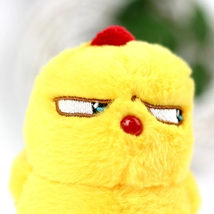 Macro detail of plush yellow chick keychain with red pom-pom and embroidery facial details