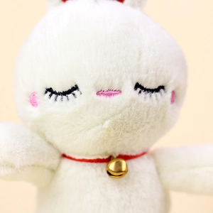 Close-up of white plush bunny with golden bell collar and detailed facial embroidery