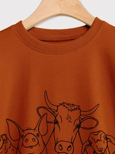 Close-up of rust crewneck sweatshirt with farm animal graphic on a wooden hanger