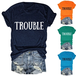 Dettaglio della maglietta in cotone con stampa TROUBLE e pantaloncini denim strappati