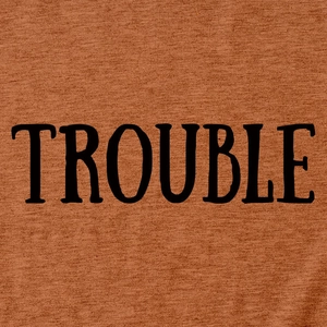 Dettaglio della scritta nera TROUBLE stampata su tessuto di t-shirt arancione ruggine