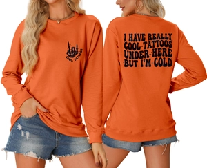 Detail view of orange crewneck sweatshirt showing front and back graphic prints