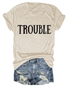 Dettaglio della maglietta in cotone beige con stampa TROUBLE e pantaloncini denim
