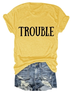 Flat lay di maglietta gialla con scritta TROUBLE e pantaloncini di jeans sfrangiati