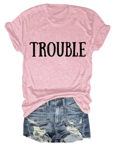 Dettaglio della t-shirt rosa in cotone con stampa TROUBLE e shorts in denim strappati