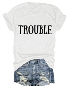 T-shirt in cotone bianco con stampa TROUBLE e shorts in denim invecchiato su piano