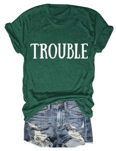 Dettaglio della t-shirt verde bosco con scritta Trouble e pantaloncini denim blu strappati