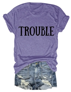 Dettaglio della t-shirt viola con scritta TROUBLE e pantaloncini di jeans strappati