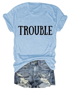Dettaglio della t-shirt girocollo azzurra con stampa TROUBLE e shorts in denim sfrangiati