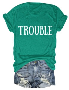 Dettaglio della t-shirt verde con scritta Trouble e pantaloncini di jeans blu