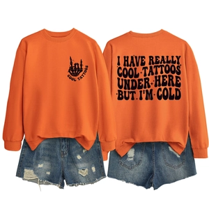 Front and back detail of orange sweatshirt with cool tattoos print and ripped denim shorts