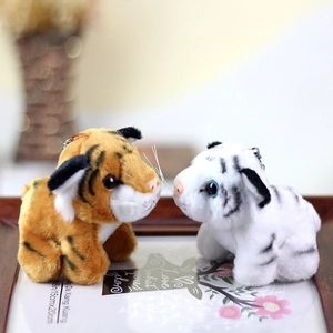 Detail of plush tiger keychains in orange and white fur sitting on a wooden tray