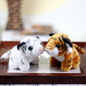 Close-up of white and orange tiger plush toys on a wooden tray with soft textures