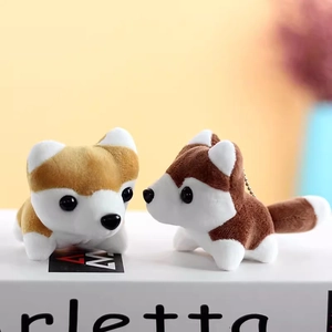 Close-up of mini husky and shiba inu plush keychains on book with soft lighting