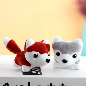 Close-up of cute husky plush keychain pair in red and grey on a white book prop