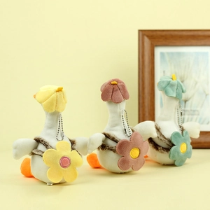 Three plush duck keychains in white with colorful floral hats and matching crossbody bags