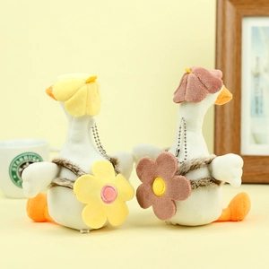 Detail of plush duck keychains with flower backpacks and soft beanies on a cozy desk