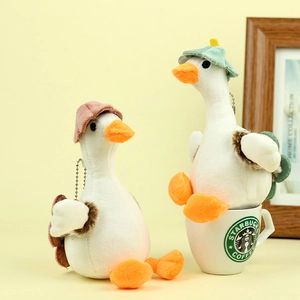 Close-up of white plush duck keychains with pink and green hats in a cozy setup