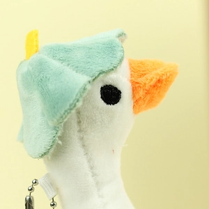 Close-up of plush white duck keychain with a cute green leaf hat and metal bead chain
