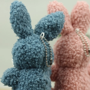 Detailed view of plush rabbit keychain with soft curly texture and pink bowtie