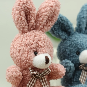 Close-up of curly plush texture and checkered bow on sitting bunny stuffed toy