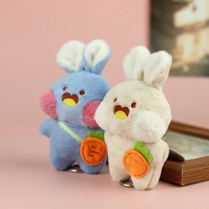 Portachiavi con coniglio di peluche e borsa a carota in blu e beige su sfondo rosa