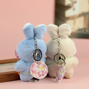 Dettaglio di ciondoli a forma di coniglio in peluche blu e beige con portachiavi d'argento