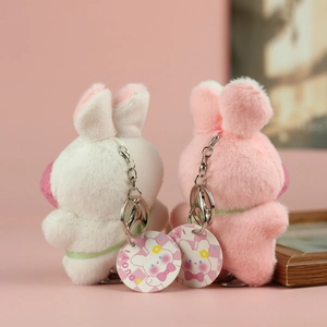 Dettaglio di portachiavi a coniglietto di peluche con catene argentate e loghi di marca