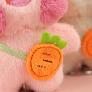 Dettaglio della trama del peluche rosa e della borsa a tracolla a forma di carota arancione