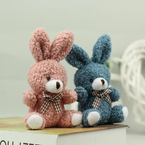 Cute long-eared bunny plush toys in pink and blue with checkered bowties on books