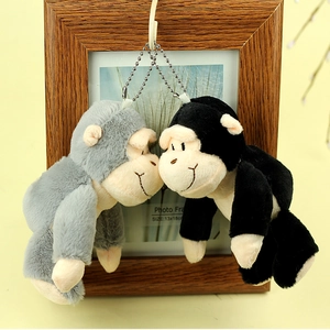 Détail des porte-clés gorilles en peluche noir et gris suspendus à un cadre en bois